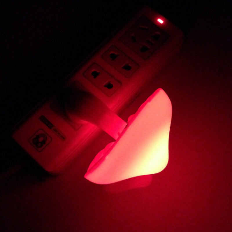 Small LED light bulb glowing red next to a power outlet.